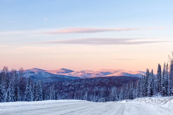 Road in the winter mountains in the background — Stock Photo, Image