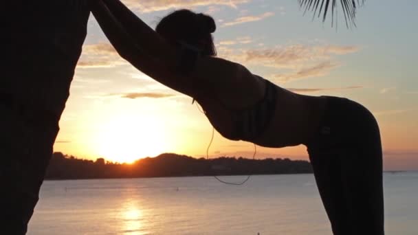 カラフルな夕日を背景にビーチで走る若い女性が — ストック動画