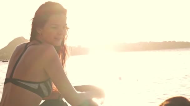 Νεαρή Γυναίκα Κάθεται Στην Παραλία Πολύχρωμο Φόντο Ηλιοβασίλεμα — Αρχείο Βίντεο