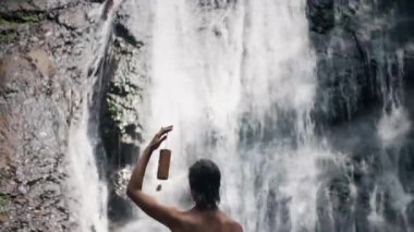 Şelalenin yanında duran kadın meditasyon yapıyor.