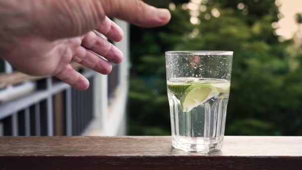 Mann Hält Glas Mit Wasser Und Limettenscheiben — Stockvideo