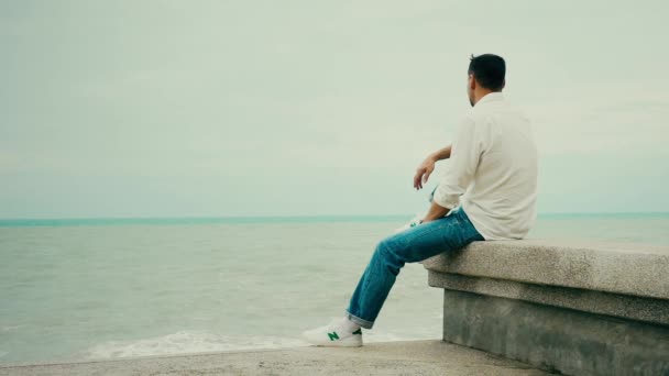 男人坐在靠近大海的码头上 — 图库视频影像