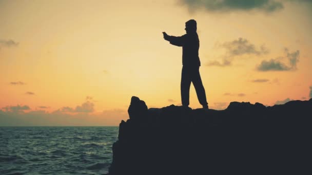 Silhouette Eines Mannes Der Bei Sonnenaufgang Auf Den Felsen Meer — Stockvideo