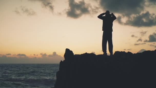 日出时一个人站在海边岩石上的轮廓 — 图库视频影像
