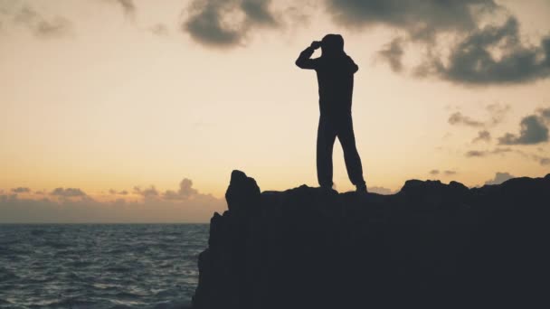 日出时一个人站在海边岩石上的轮廓 — 图库视频影像