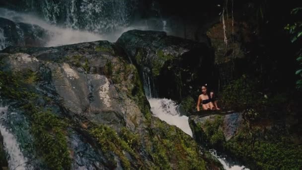 Девушка Сидит Скалах Смотрит Водопад Тропиках Солнечный Летний День — стоковое видео