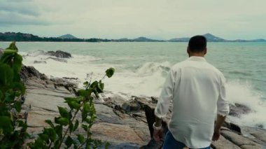 Sahilde yürüyen bir adamın yavaş çekim videosu. 