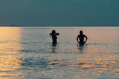 Sahilde bir kadın ve erkeğin silueti.