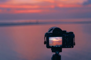 Fotoğrafçı gün batımında sahilde fotoğraf çekiyor.