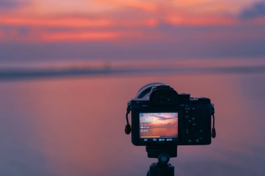 Fotoğrafçı gün batımında sahilde fotoğraf çekiyor.