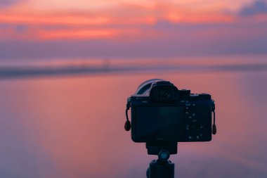 Fotoğrafçı gün batımında sahilde fotoğraf çekiyor.