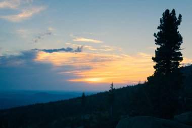 Güneş yazın bir dağ vadisinde batıyor. Gün batımında sıradağların manzarası. Yukarıdan görüntüle
