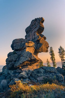 Gün batımında mavi gökyüzüne karşı dağın tepesinde kayalar.