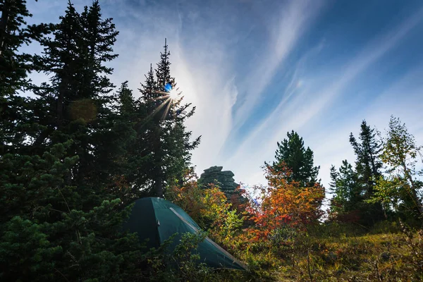 青空と沈む夕日を背景に 秋の森の中の山の頂上に立つ観光テント — ストック写真