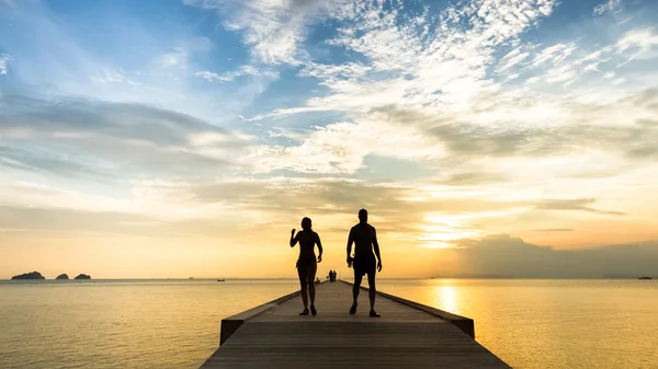 Пара прогулок по пирсу на закате на тропическом острове — стоковое фото