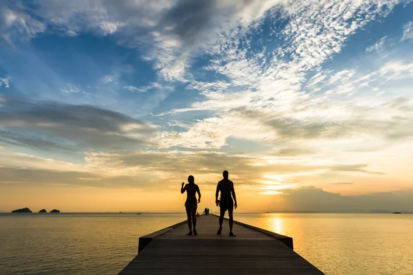 夫妻在码头上在日落时分在一个热带岛屿上散步 — 图库照片