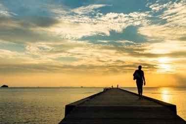 İskelede günbatımında tropik bir adada yürüyen kadın. Koh Samui, Tayland