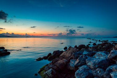 Bir tropik ada plaj gün batımı. Denizde büyük taşlar.