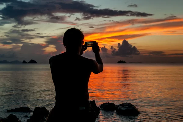 Telefonunuz bir tropik ada ve güneşin çekim kıyısında ayakta adam — Stok fotoğraf