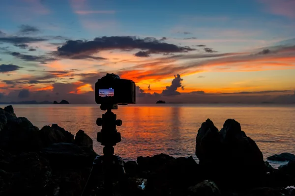 La cámara de pie en la playa de una isla tropical y fotografiado puesta de sol — Foto de Stock