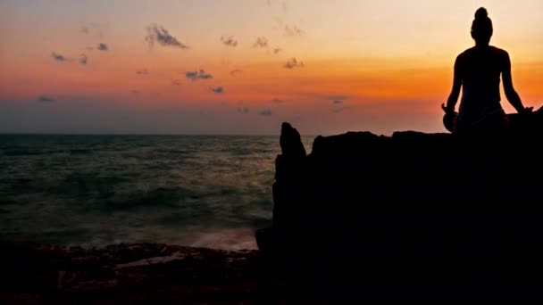 Die Frau meditiert auf einem Felsen am Strand bei Sonnenaufgang auf einer tropischen Insel koh samui, Thailand. — Stockvideo