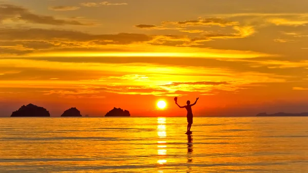 Silueta de un hombre de pie en el mar al atardecer islas fondo en una isla tropical —  Fotos de Stock