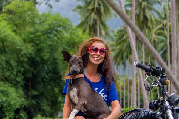 Женщина сидит на велосипеде и держит собаку — стоковое фото