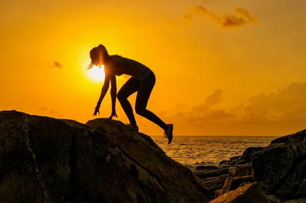 Menina corre ao longo das rochas no fundo de um amanhecer de verão — Fotografia de Stock