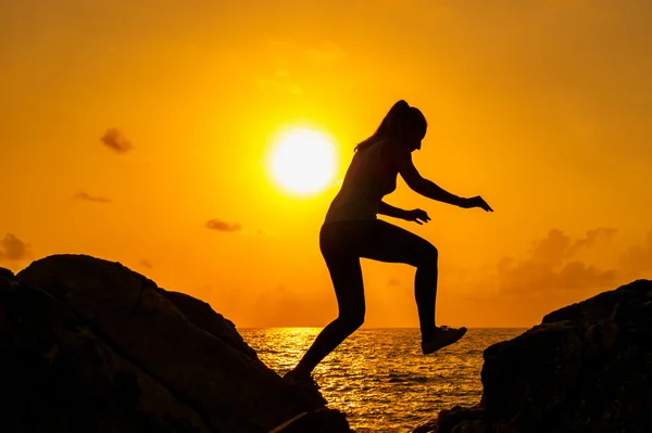 Chica corre a lo largo de las rocas en el fondo de un amanecer de verano — Foto de Stock