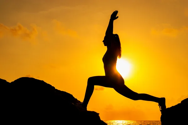 Silhouette di donna che fa yoga sulle rocce — Foto Stock