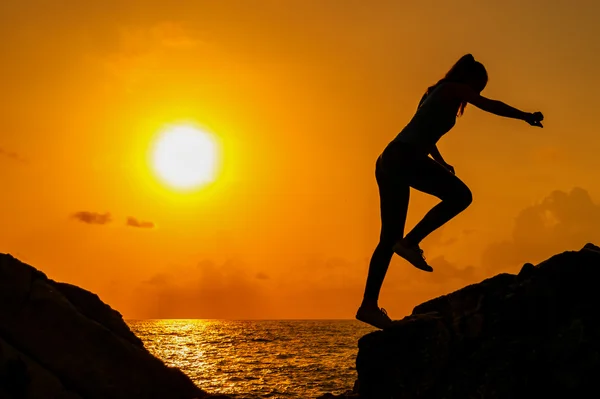 Menina corre ao longo das rochas no fundo de um amanhecer de verão — Fotografia de Stock