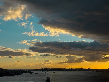 İstanbul Boğazı 'nda, Silüet Tarihi Yarımada ve Gemilerin Üzerinde Dramatik Günbatımı. Karanlık bulutların altında yüzen ünlü camileri ve gemileri olan tarihi yarımadanın siluetleri..