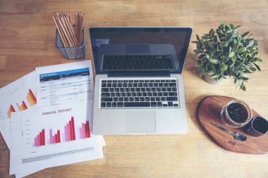 Ofis dizüstü bilgisayarının finansal döküman şeması ve kahve fincanı ile ahşap masanın üzerindeki grafiği. Düz dizüstü bilgisayar ofis masasında duruyordu. İş sahasında iş grafiği modellemesi yok