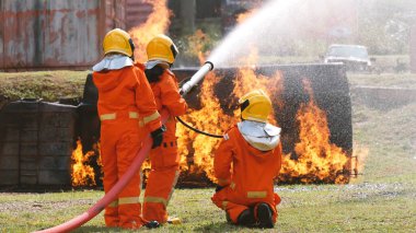 İtfaiyeci yangın hortumuyla, kimyasal köpüklü sprey motorla savaşıyor. İtfaiyeciler korunmak için kasketli, vücut korumalı üniformalı üniforma giyer. Yangın söndürücüde kurtarma eğitimi.