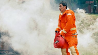 İtfaiyeci yangın hortumuyla, kimyasal köpüklü sprey motorla savaşıyor. İtfaiyeciler korunmak için kasketli, vücut korumalı üniformalı üniforma giyer. Yangın söndürücüde kurtarma eğitimi.
