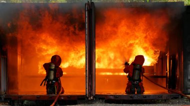 İtfaiyeci yangın hortumuyla, kimyasal köpüklü sprey motorla savaşıyor. İtfaiyeciler korunmak için kasketli, vücut korumalı üniformalı üniforma giyer. Yangın söndürücüde kurtarma eğitimi.