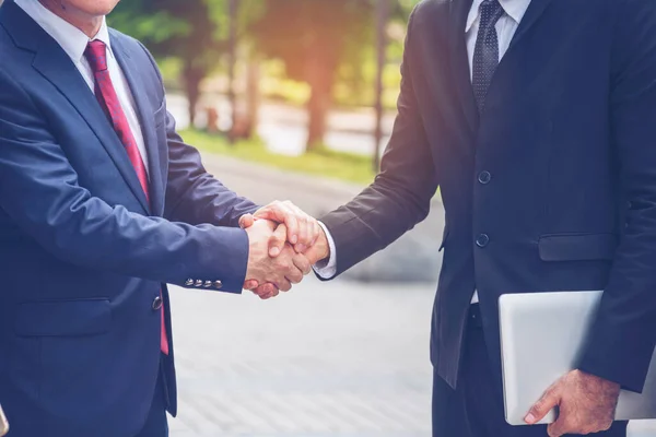 Team Business Partners shaking hands together to Greeting Start up new project. Shakehand Teamwork Partnership outside office modern city background. Businessman handshake together.  Business concept