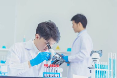 İki Asyalı bilim adamı kimya bilimi tüpü deney tüpü antikor örneğini kovid-19 virüsüne karşı laboratuvar geliştirmek için depoluyorlar. Kimya Laboratuarı 'nda bilim adamı danışmanı, analizi