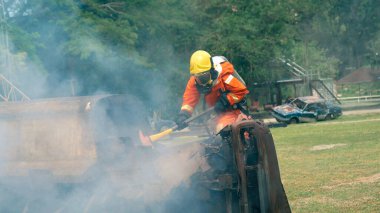 İtfaiyeci yangın hortumuyla, kimyasal köpüklü sprey motorla savaşıyor. İtfaiyeciler korunmak için kasketli, vücut korumalı üniformalı üniforma giyer. Yangın söndürücüde kurtarma eğitimi.