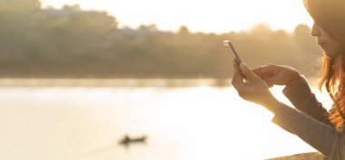 Banner Woman 'ın elleri cep telefonunu tutuyor internette internet teknolojisi üzerinde sörf yapıyor. Akıllı telefon cihazını kullanarak kadın eli kapat. Kopya alanı olan panoramik bir mesaj gönder. Teknoloji yaşam tarzı