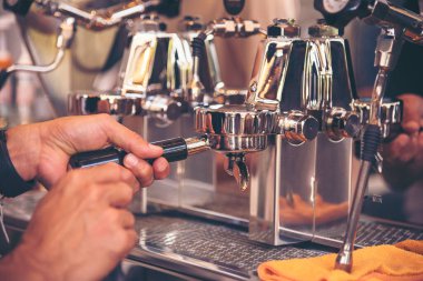 Kahve barmeni kahve makinesinden espresso shot yapar. İtalyan kafeteryasında sütlü kapuçino. Kahve makinesinin ellerini kapat. Müşteri kafeteryası için kahverengi latte yap..