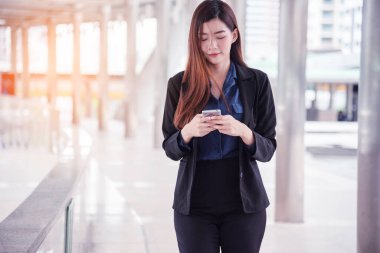 İş kadını internet üzerinden akıllı telefon alışverişi yapıyor, arıyor, internet teknolojisi yaşam tarzı mesaj yolluyor. Şehir caddesinde cep telefonu kullanan Asyalı kadın. Akıllı telefon akıllı, kendine güvenen kadın modern şehir.