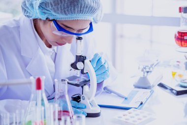 Kadın bilim adamı mikroskopa bakar, bilim test tüpü laboratuvar araştırma deneylerindeki bilimsel örnekleri analiz eder ve biyoteknoloji virüse karşı aşı üretir. Kimya bilimi laboratuarı kavramı