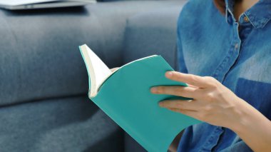 Oturma odasında kitap okuyan Asyalı kadın kitap okuyacak. Genç kadın gevşeme okuyucusu açık kitap boş zihin okuyor. Mutluluk, güzel kadın, gülen surat, mutlu zaman.