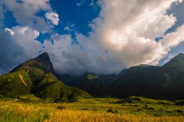 Güneşli bir günde güzel bir manzara, yeşil çayır, beyaz bulut, mavi gökyüzü. Görkemli yeşil manzara büyük dağ tepesi bulutlu vadi manzarası kırsal yeşil çayır manzarası