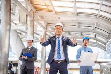 İnşaat mühendisi takım çalışması güvenlik ekibi, inşaat sahasında beyaz sarı şapkalı güvenlik ekipmanı tutuyor. Hardhat İnşaat Mühendisliği Mühendisliği Yöneticisini Koru