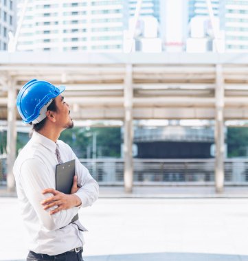 İnşaat mühendisi elleri inşaat mühendisliği için beyaz kaskı tutuyor. İnşaat mühendisi takım elbiseli adam inşaat sahasında beyaz kasklı kaskı elinde tutuyor.