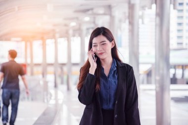 İş kadını internet üzerinden akıllı telefon alışverişi yapıyor, arıyor, internet teknolojisi yaşam tarzı mesaj yolluyor. Şehir caddesinde cep telefonu kullanan Asyalı kadın. Akıllı telefon akıllı, kendine güvenen kadın modern şehir.