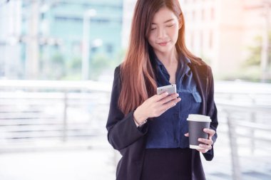 İş kadını internet üzerinden akıllı telefon alışverişi yapıyor, arıyor, internet teknolojisi yaşam tarzı mesaj yolluyor. Şehir caddesinde cep telefonu kullanan Asyalı kadın. Akıllı telefon akıllı, kendine güvenen kadın modern şehir.