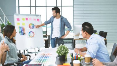 Çeşitli etnik gruplardan oluşan bir grup iş adamı konferans odasında toplantı yapıyor. İş grafiği, grafik ve veri bilgileriyle beyin fırtınası yapıyorlar. Takım çalışması iş birliği yapar. Güven ortakları bir araya gelir.